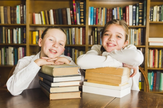 smiling-girls-sitting-with-piles-books