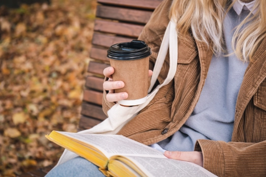 young-woman-sits-bench-autumn-park-drinks-coffee-reads-book